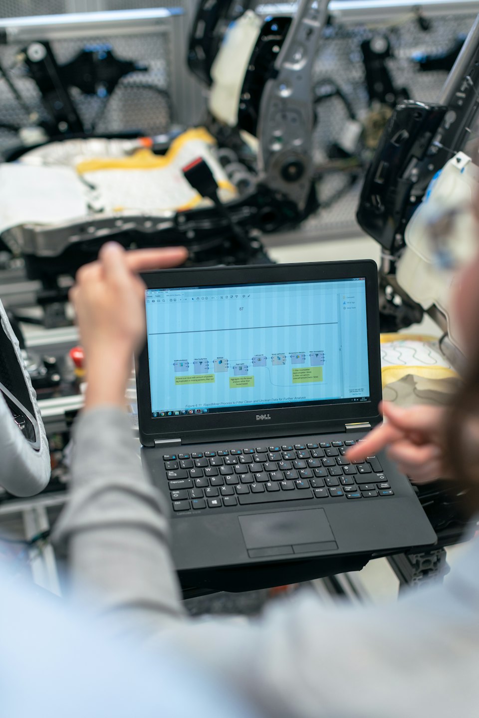 Two people reviewing a data flowchart on a laptop screen.