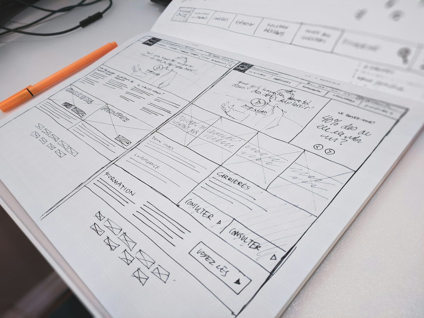 Notebook with website wireframes and sketches on a desk.