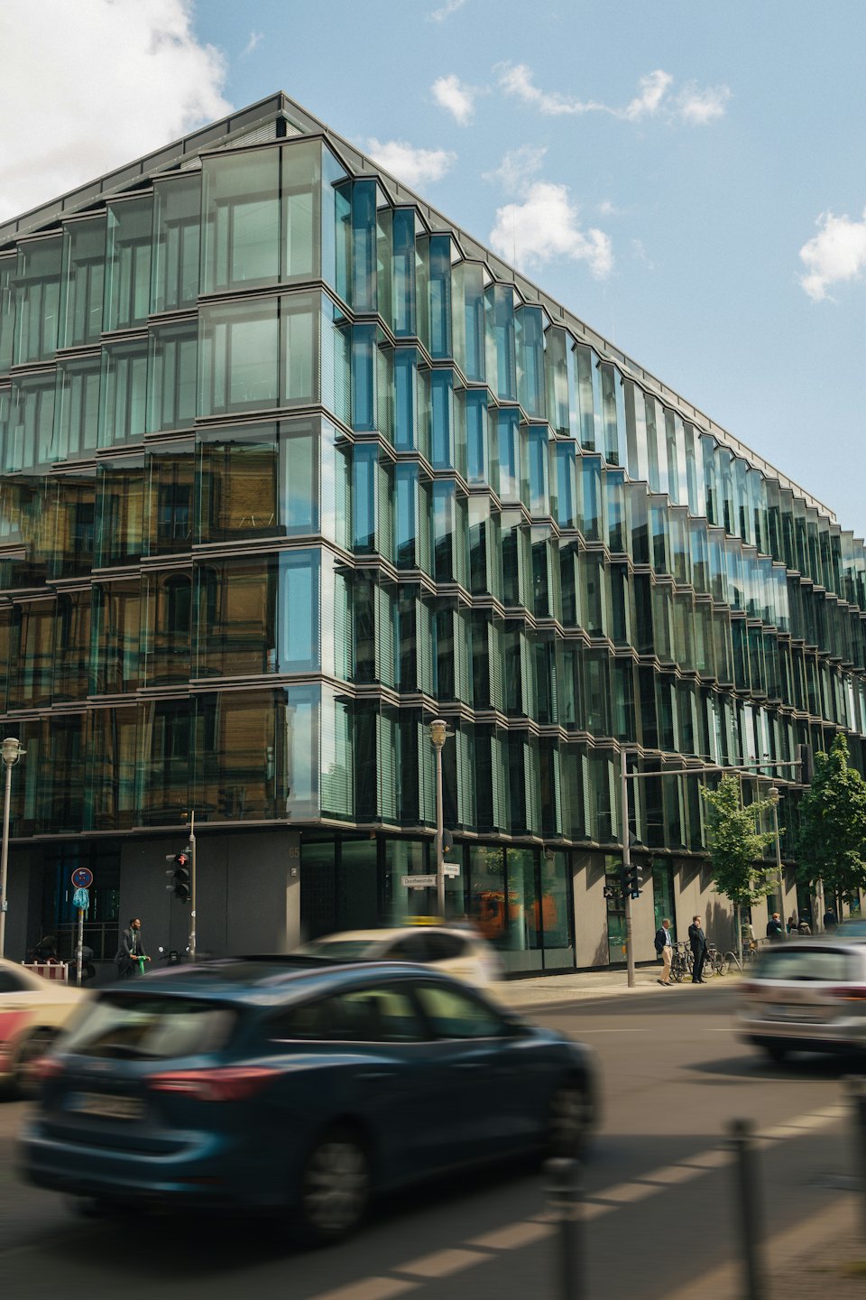 Modern glass office building standing at a busy city intersection.